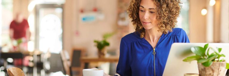 Young woman working at a desk with laptop and cup of coffee