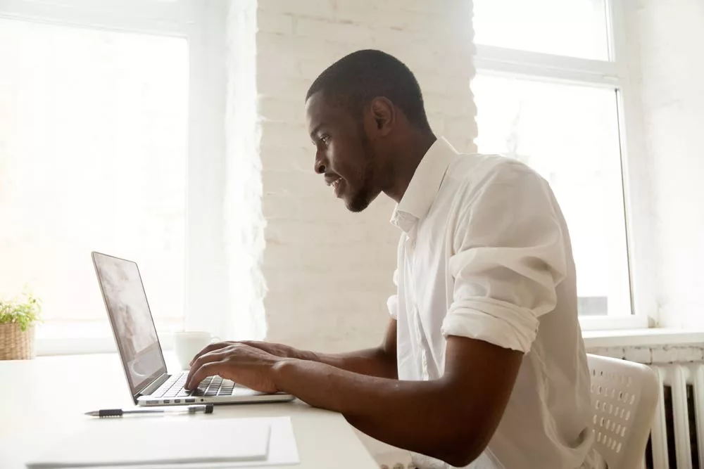 Young professional sitting at the desk and working on the laptop